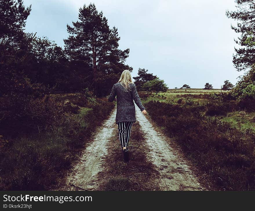 Woman in Grey Cardigan With Grey and Black Striped Pants Walking at the Pathway