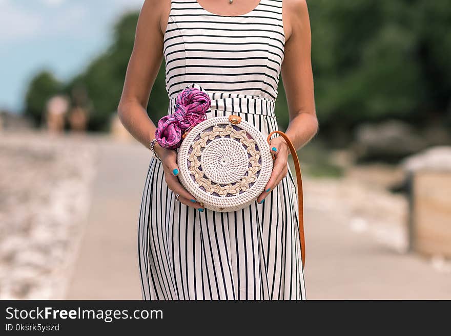 Woman Wearing White And Black Striped Sleeveless Dress Holding Round Crochet Bag