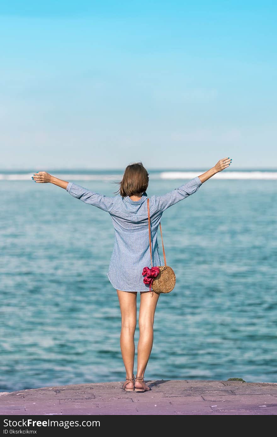 Woman In Blue Dress Shirt Standing Near Body Of Water