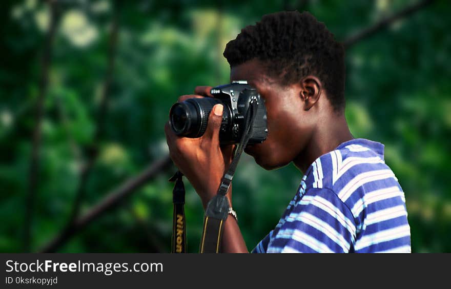 Man Wearing Blue And White Striped Shirt Using Nikon Camera