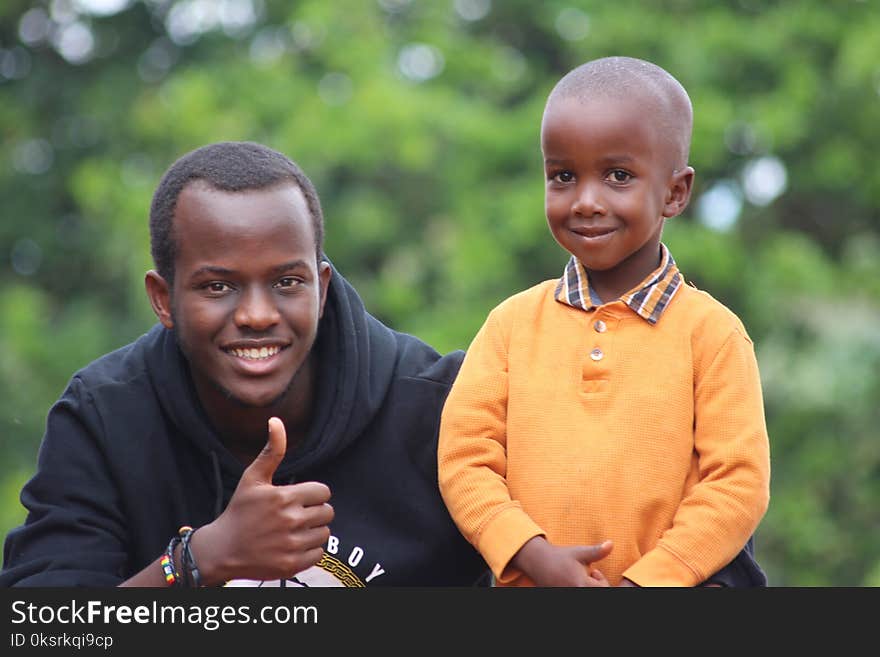 Man Wearing Black Hoodie Beside Boy Wearing Orange Long-sleeved Polo Shirt