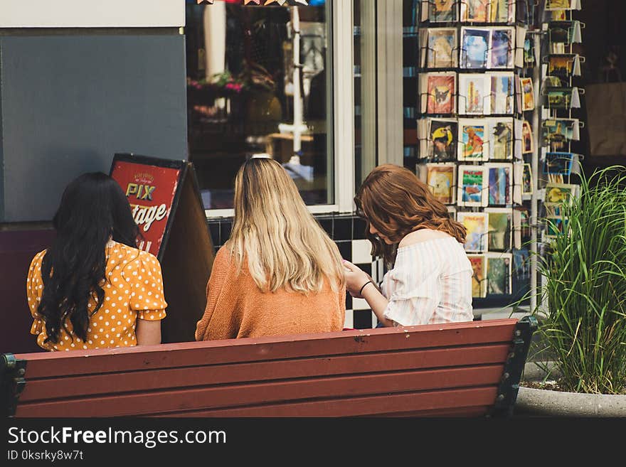 Three Women Sitting On Brown Bench