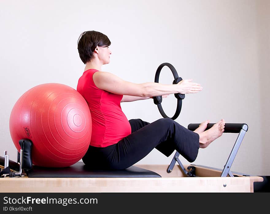 Woman in Red Shirt Sitting on Fitness Equipment