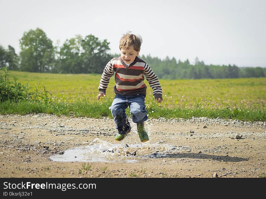 Boy Jumping Near Grass at Daytime