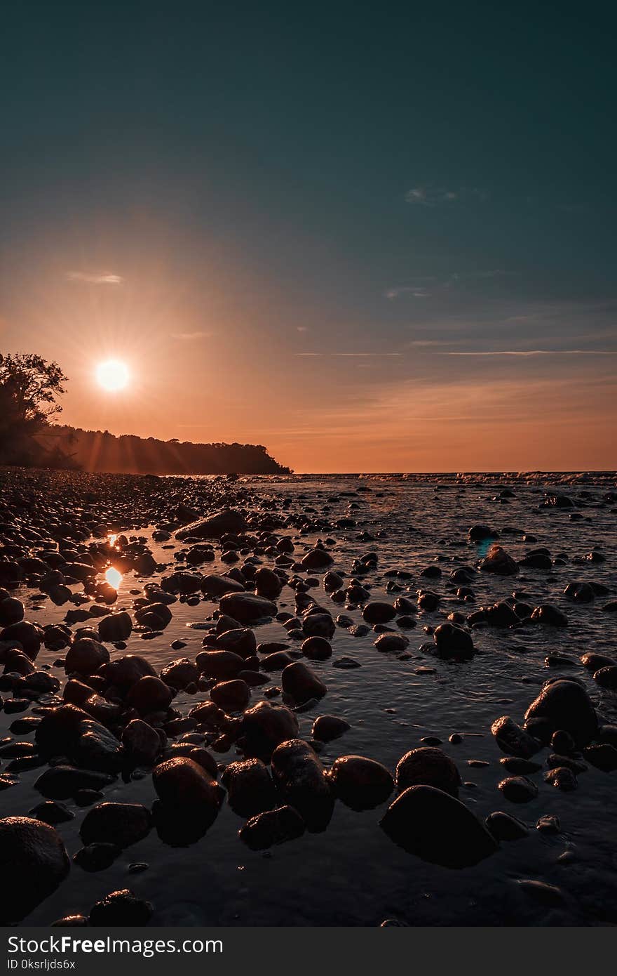 Photo Of Rock Rubles Beside Calm Body Of Water during Golden Hour