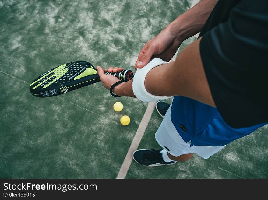 Person Holding Black and Green Tennis Racket