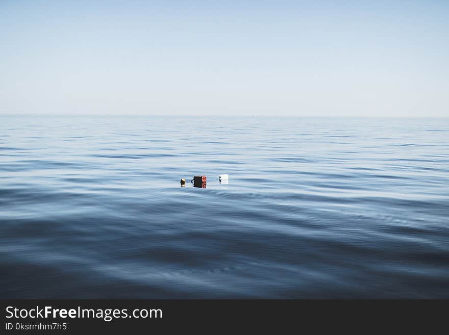 Three Red and White Floating Objects on Water