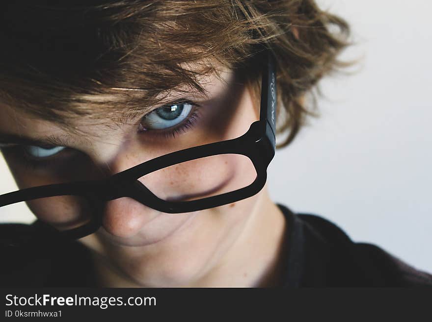 Woman in Black Top and Black Framed Eyeglasses Near White Wall