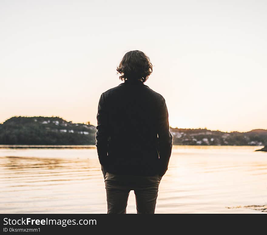 Man Standing Facing Body of Water