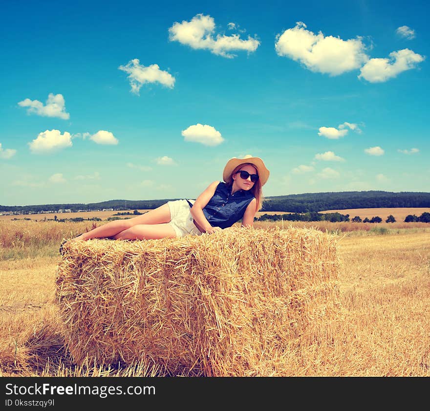 Woman lying on straw bale.