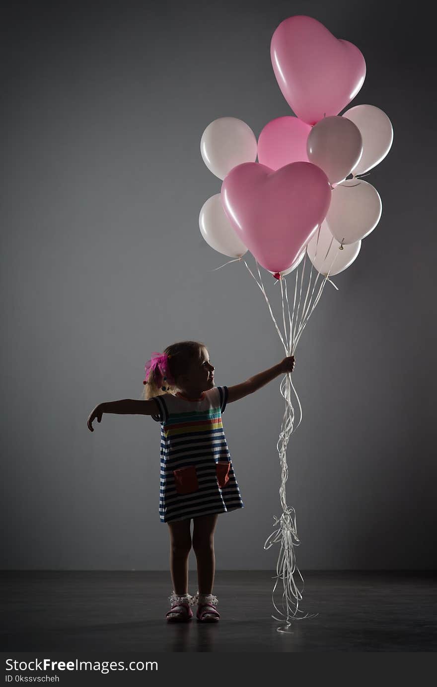 A girl four years old on a gray background with balloons. A girl four years old on a gray background with balloons