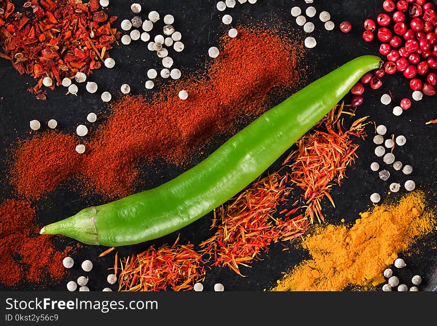 Spicy background with Fresh Chili pepper and allspice peppers and mix of other spices over black background. Top view. With space for text. Spicy background with Fresh Chili pepper and allspice peppers and mix of other spices over black background. Top view. With space for text