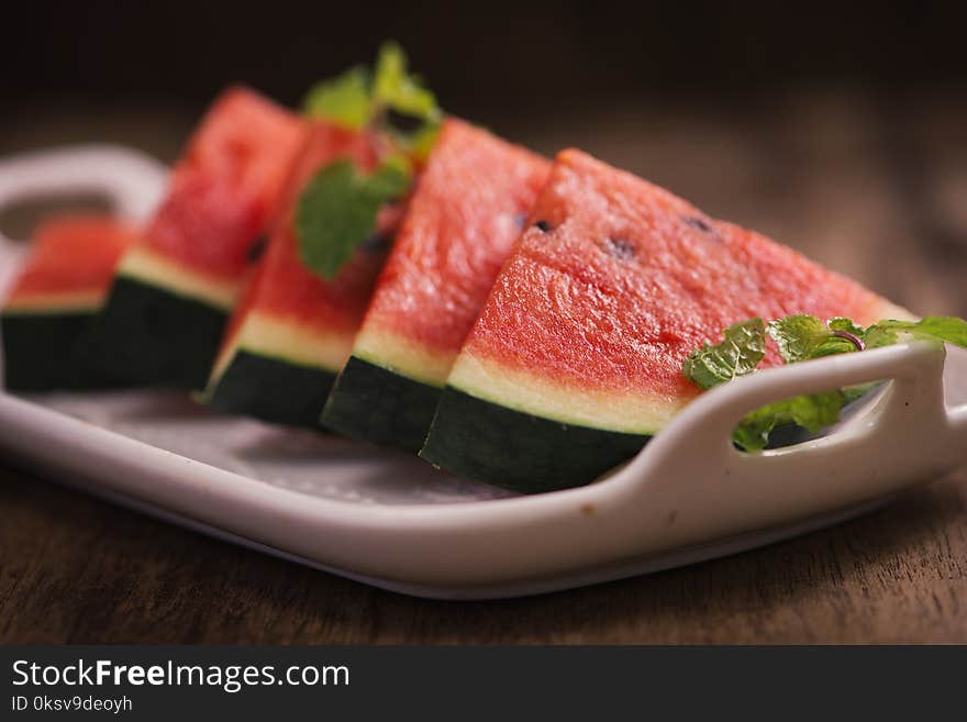 Fresh sliced watermelon in white dish on wooden table.