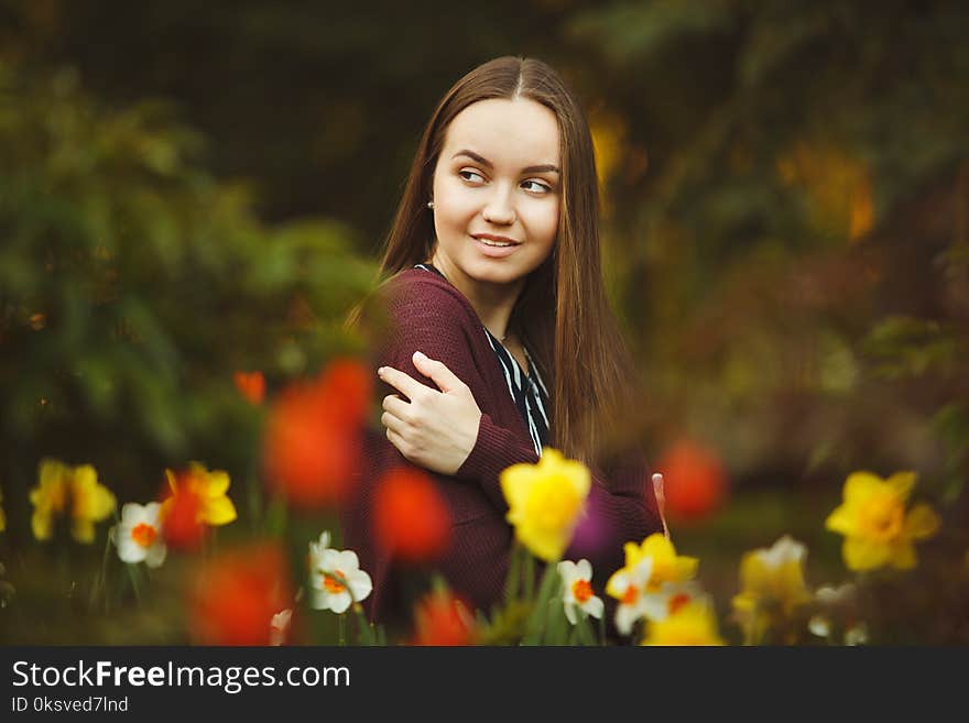 Beautiful girl sits at the planted flowers.