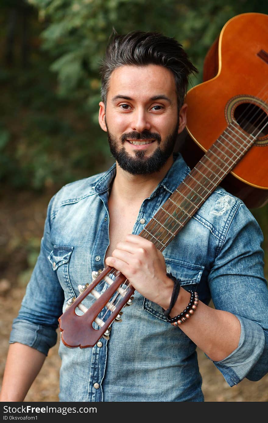 Attractive guy with clasic guitar looking at camera