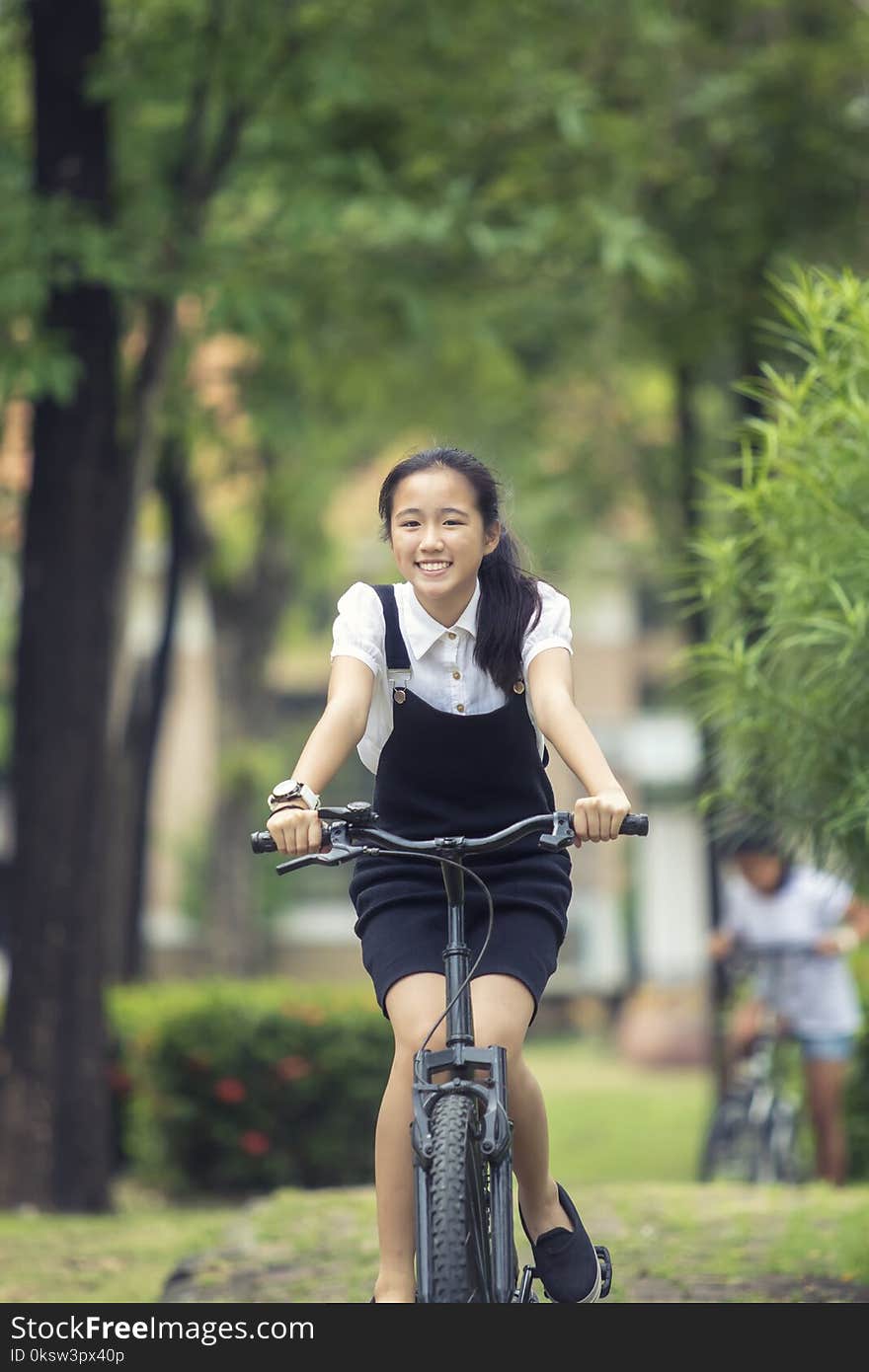 Toothy smiling face of asian teenager riding bicycle in green pa