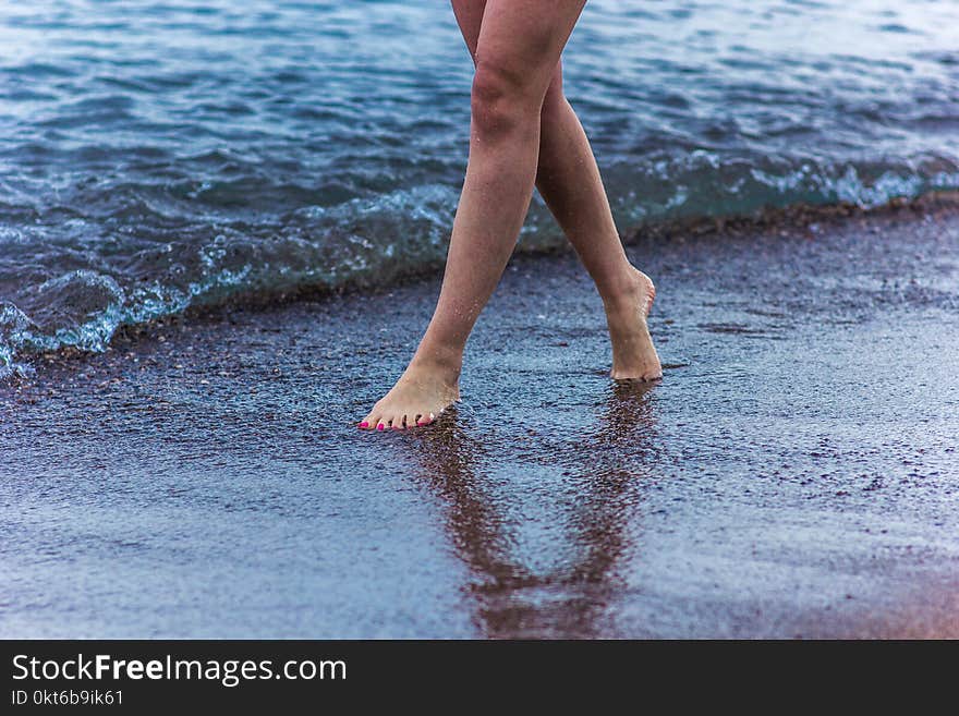 The girl is walking along the seashore, beautiful legs