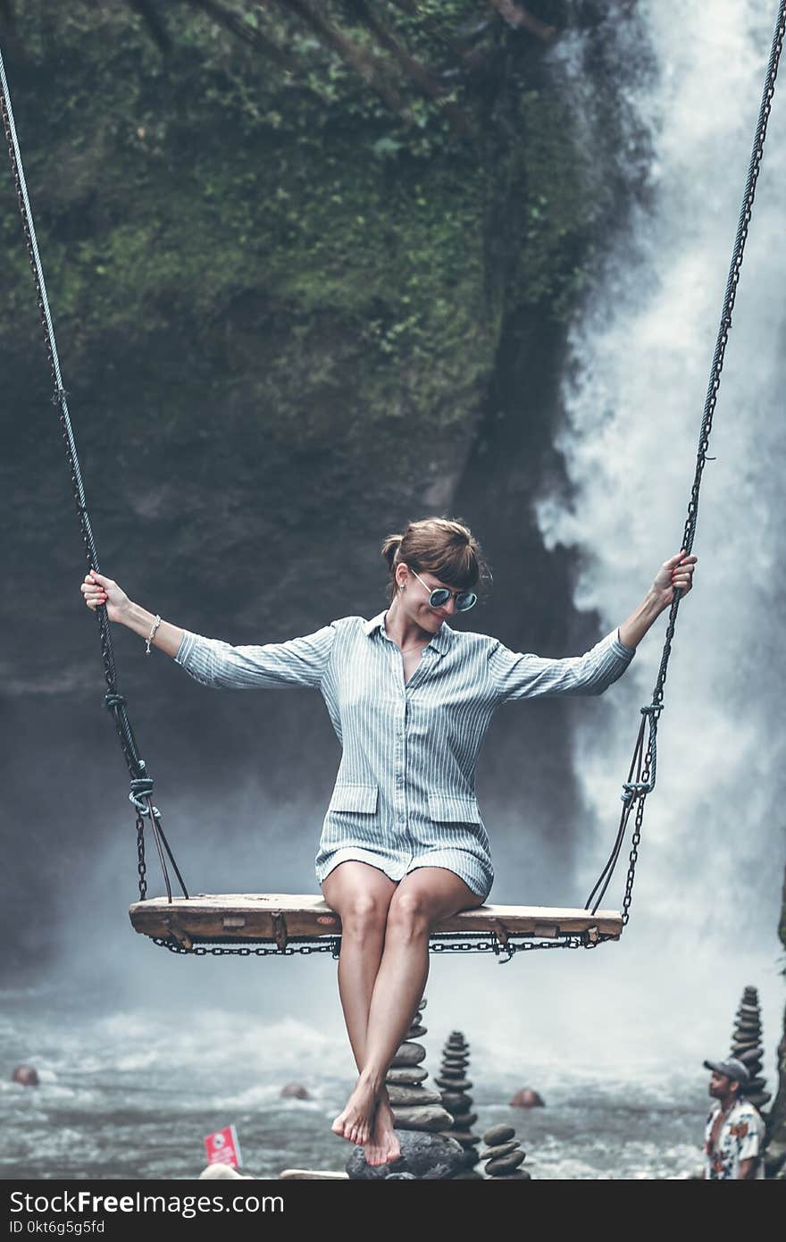 Beautiful woman swings near waterfall in the jungle of Bali island, Indonesia.