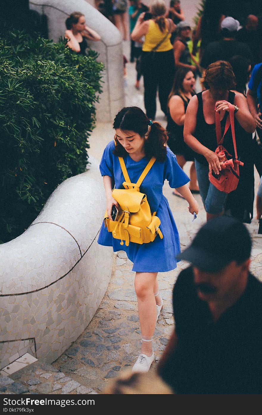 Woman in Blue Dress With Yellow Knapsack Walking Near People