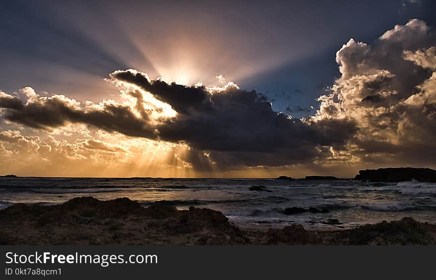 Body of Water Under Clouds With Sun Rays