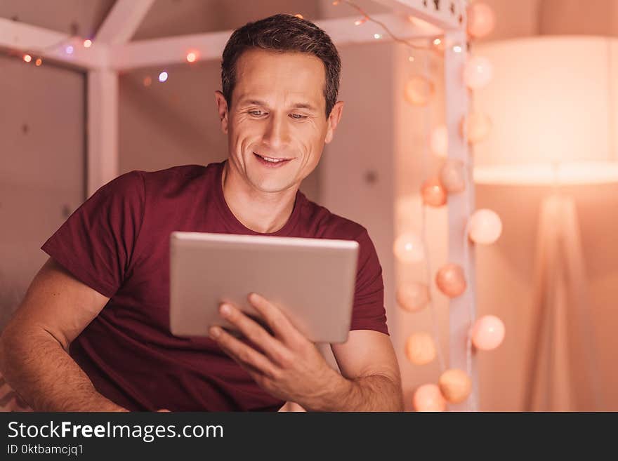 Cheerful young man looking at the tablet screen