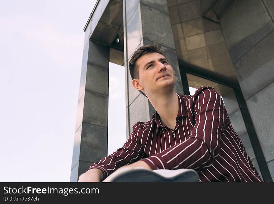 Man in Red and White Striped Dress Shirt Posing Near Wall