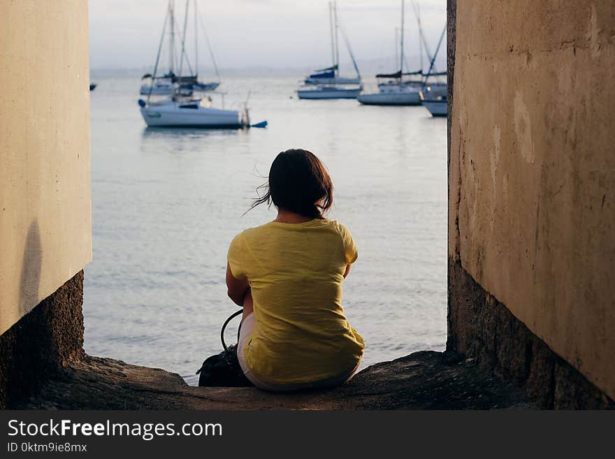 Woman in Yellow Shirt Sitting Near Body of Water