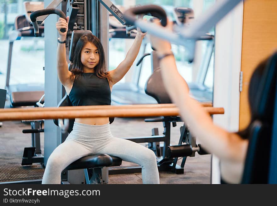 Woman in Black Sleeveless Crop-top and White Leggings Using a Butterfly Machine in Front of a Mirror