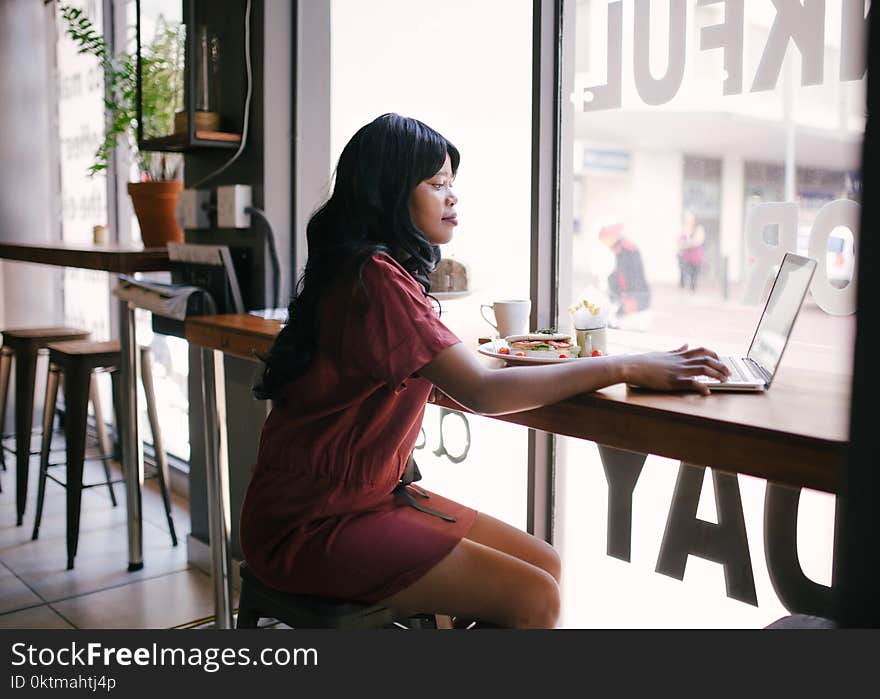 Woman in Red Dress Using Laptop on Table