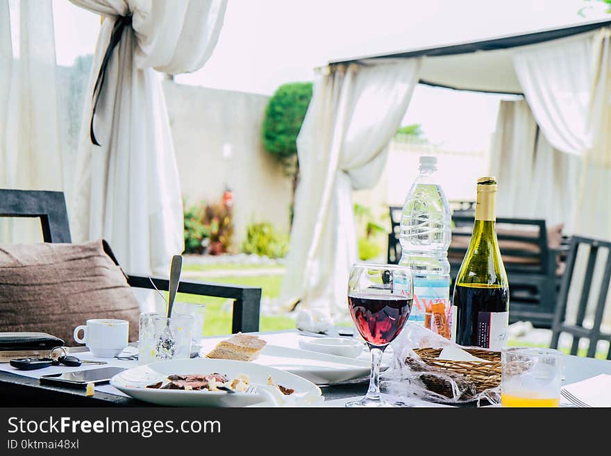 Table Full With Plate of Foods, Wine Bottle, and Mugs