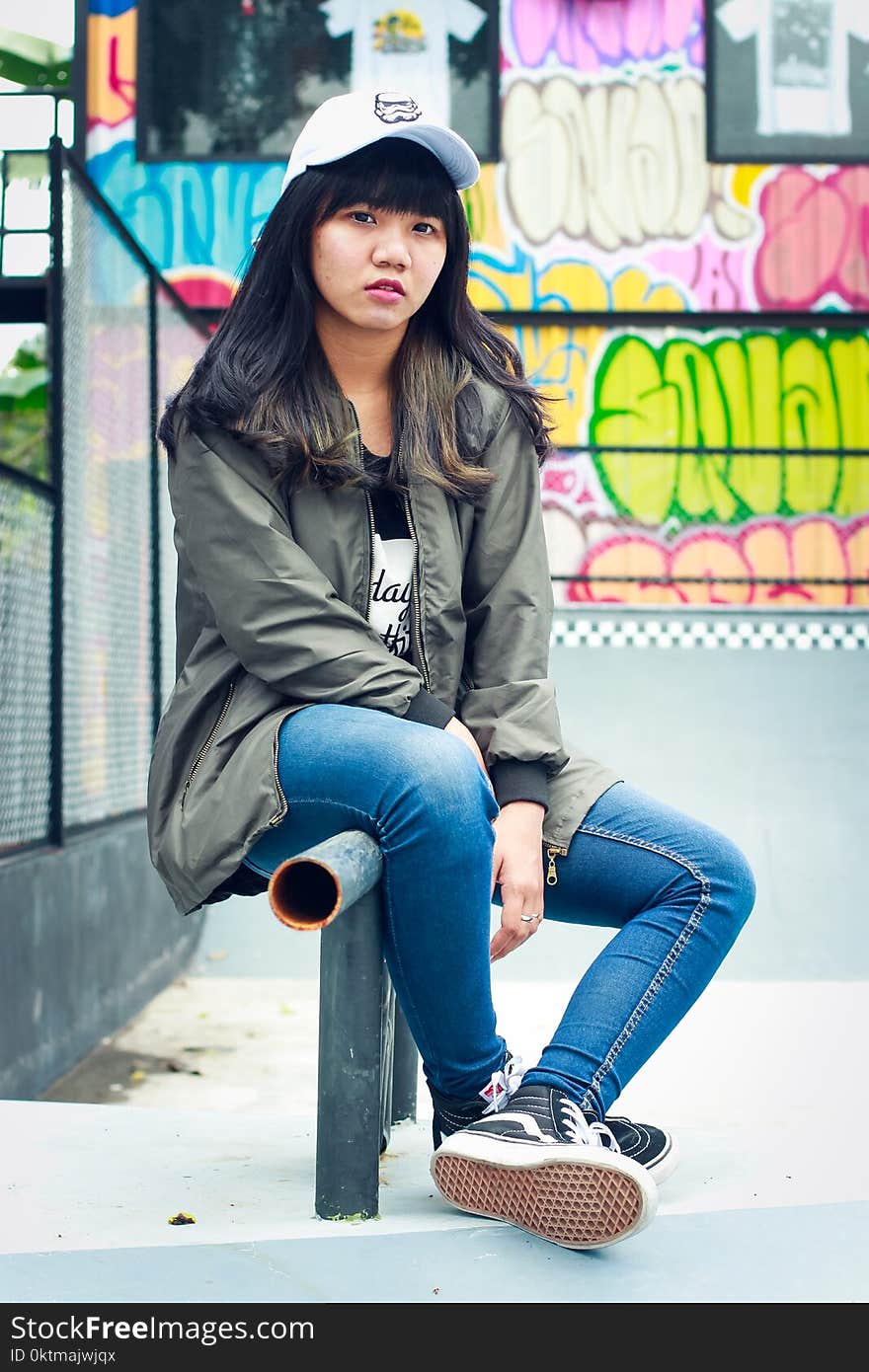 Woman in Black Zip-up Jacket Sit on Black Metal Rail