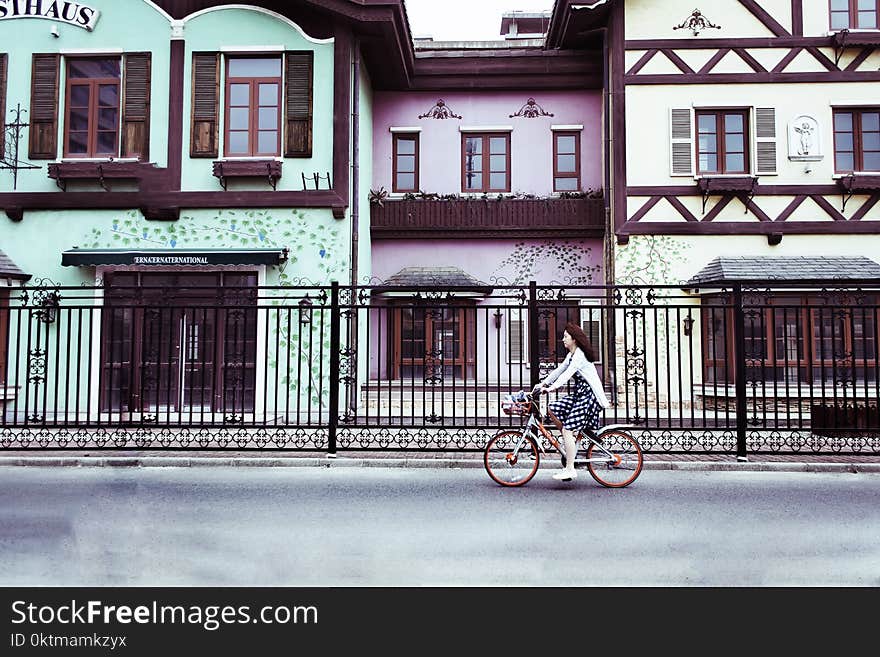 Woman Riding on Bicycle Near Concrete Houses