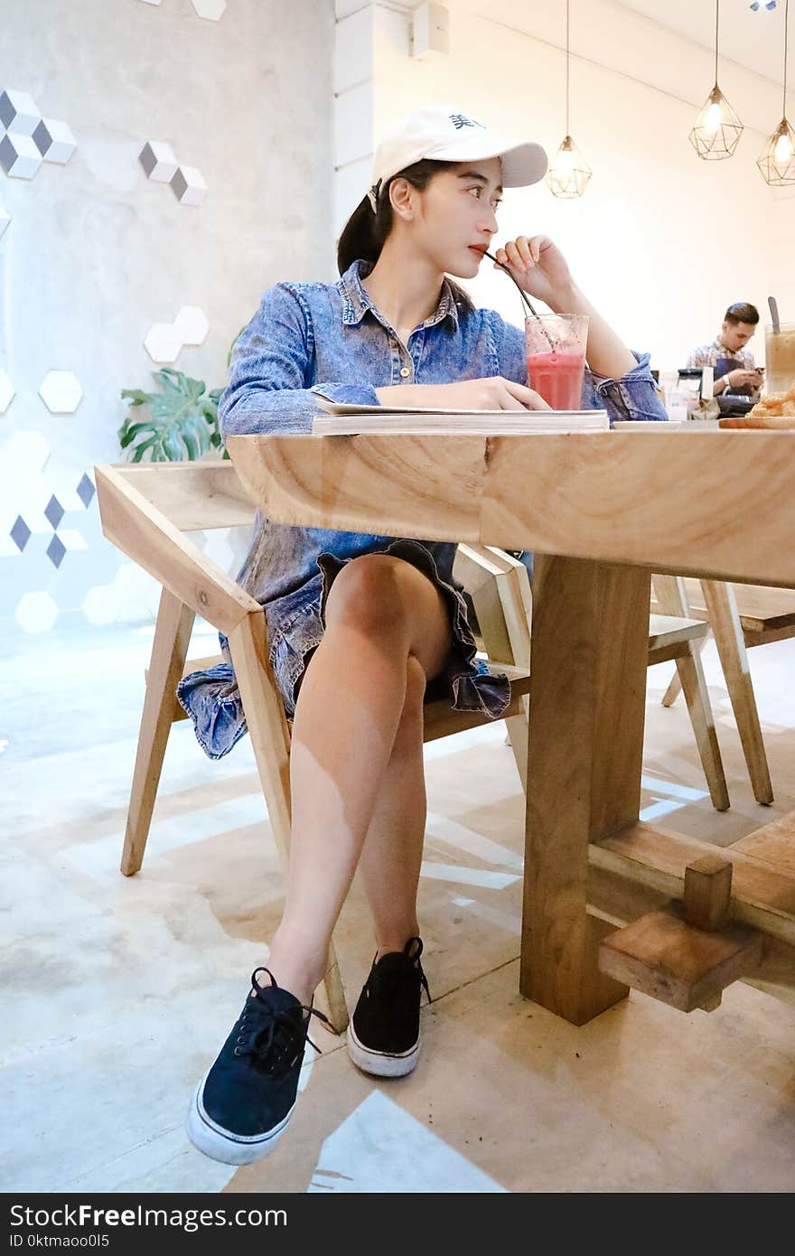 Woman Sits on Brown Wooden Chair Near Brown Table Inside Room