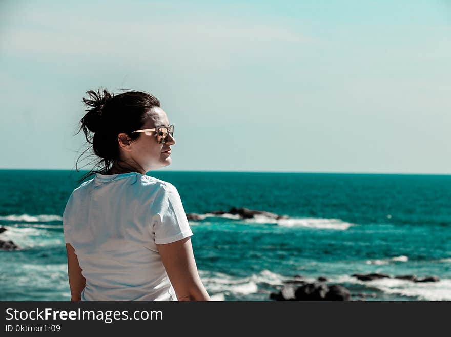 Woman Wearing White T-shirt With Distance at Sea With Rock Formations