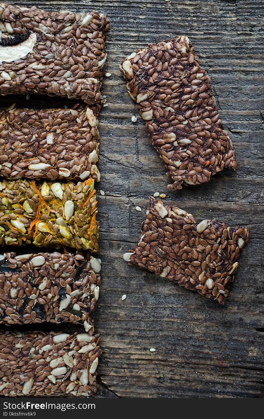 Fitness dietary food. Raw diet breadsticks with flax and sunflower seeds on rustic wooden board. Every product has filler with a mashrooms, carrot or algae. Vegan healthy nutrition concept. Top view. Fitness dietary food. Raw diet breadsticks with flax and sunflower seeds on rustic wooden board. Every product has filler with a mashrooms, carrot or algae. Vegan healthy nutrition concept. Top view.