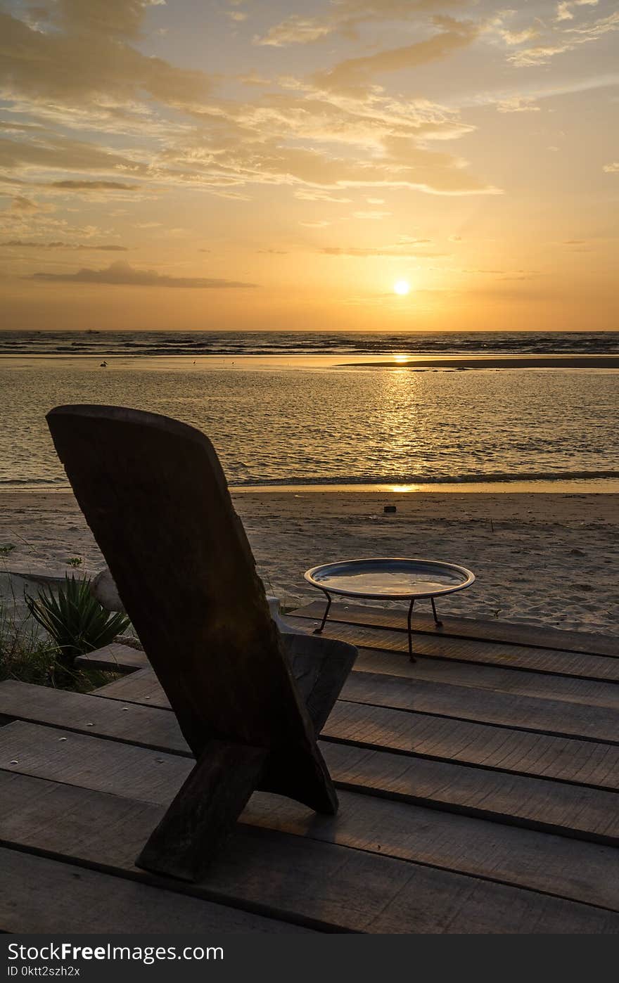 Traditional wooden African chair on terrasse at beach overlooking the ocean during beautiful sunset, Senegal, Africa.