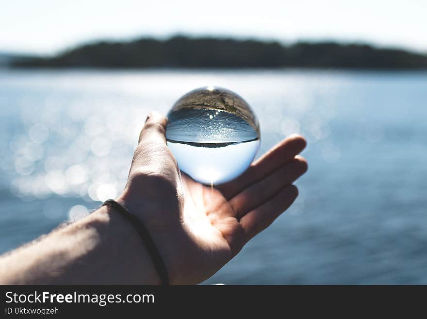 Bokeh Photography of Person Holding Water Drop