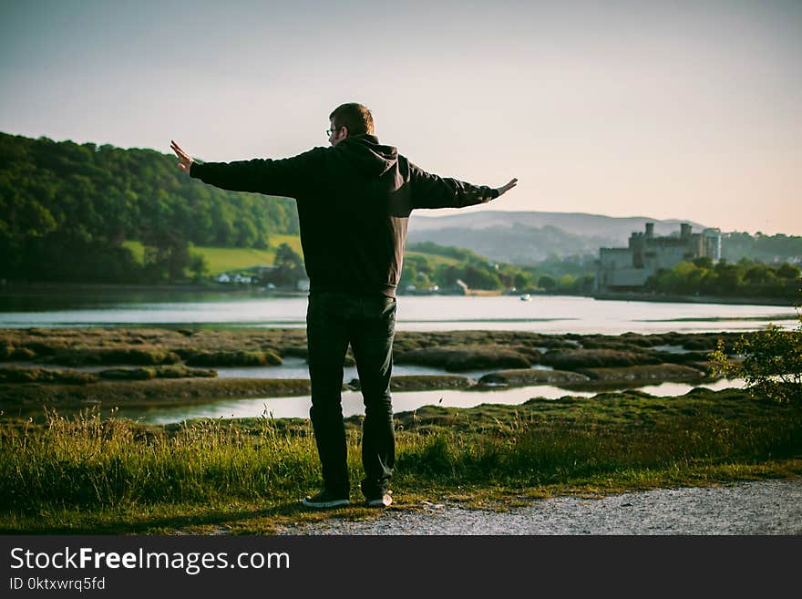 Man Wearing Black Jacket Near on Body of Water