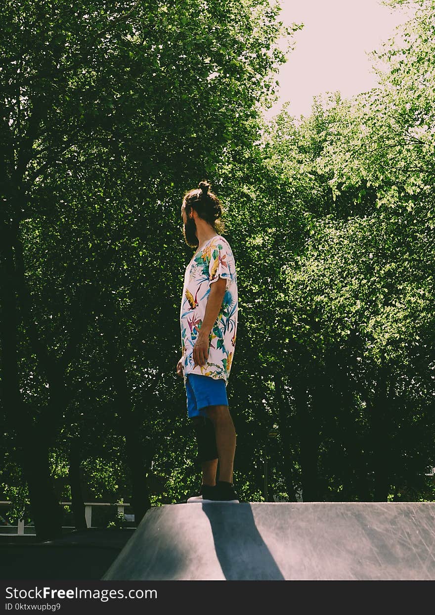 Man Wearing White and Multicolored Floral Standing Near Trees