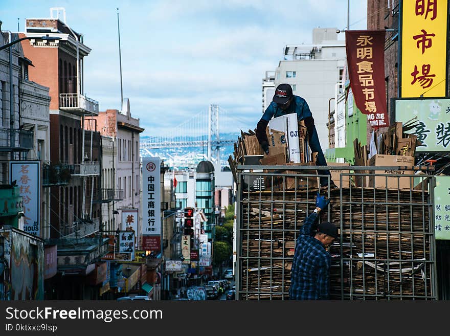 Man on Top of Truck Arranging Brown Cardboard Boxes