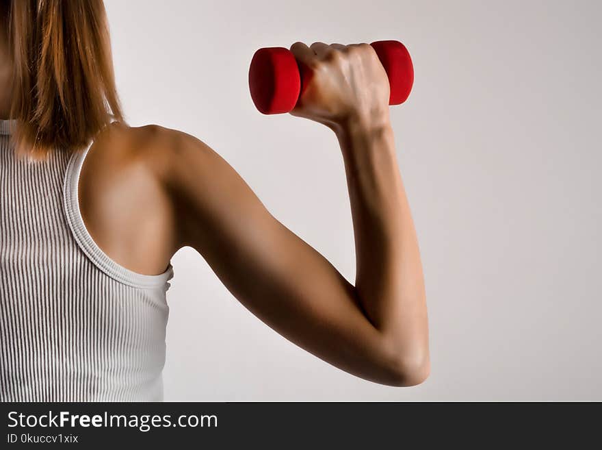 Fitness model woman hand with yellow dumbbell on gray studio background. Bodybuilding, healthy lifestyle and sport concept. Low key and close up