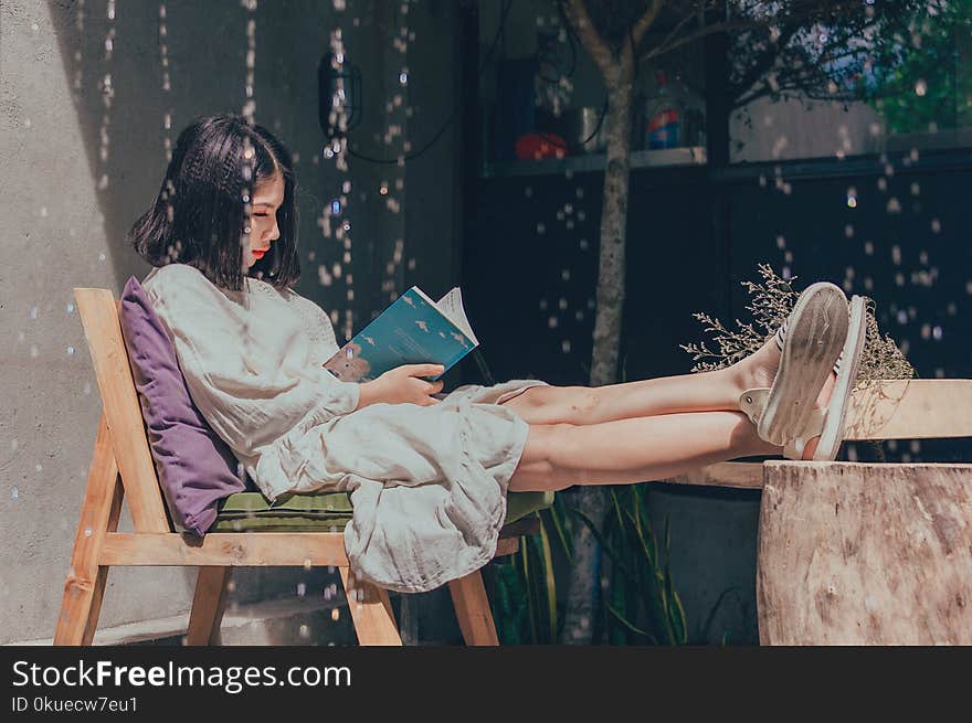 Woman Sitting on Chair While Reading Book