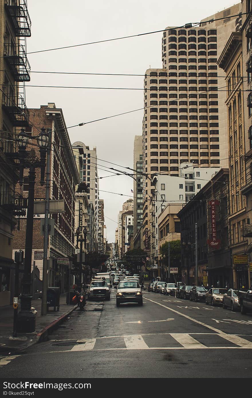 Cars on Street Surrounded by Buildings Under Dark Sky