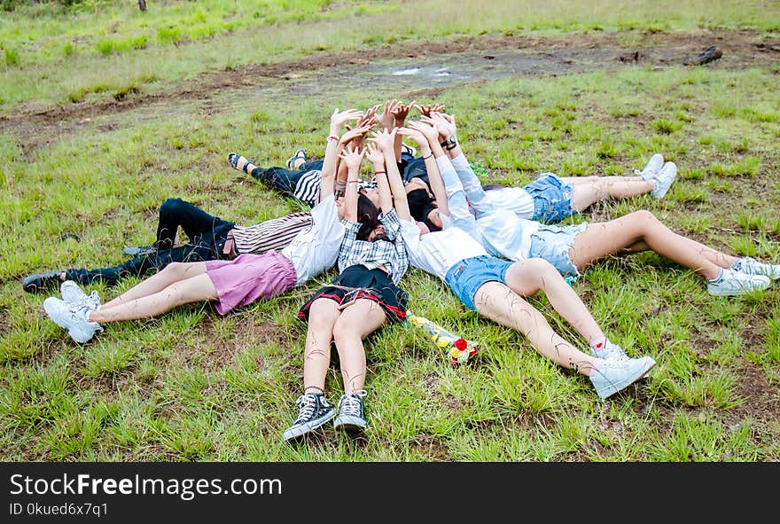 Group of Friends Form in Circle While Lying on the Grass While Hands on Top