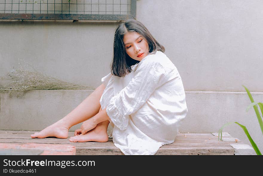 Woman in White Top Sitting on Brown Surface