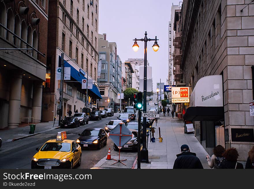 White Taxi on Road Between Buildings at Daytime