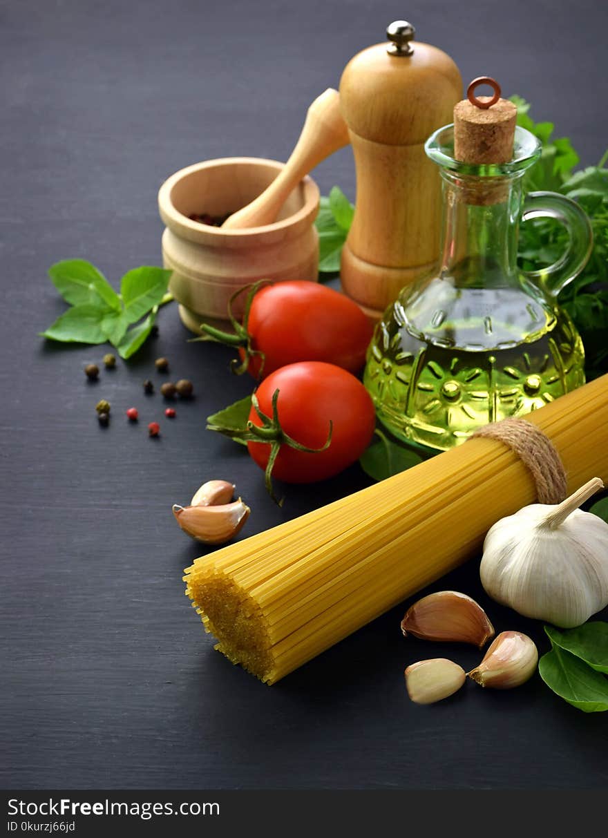 Preparing to cook pasta. Spaghetti, tomatoes, garlic, cheese grater,greens and spices on black background top view. Preparing to cook pasta. Spaghetti, tomatoes, garlic, cheese grater,greens and spices on black background top view.