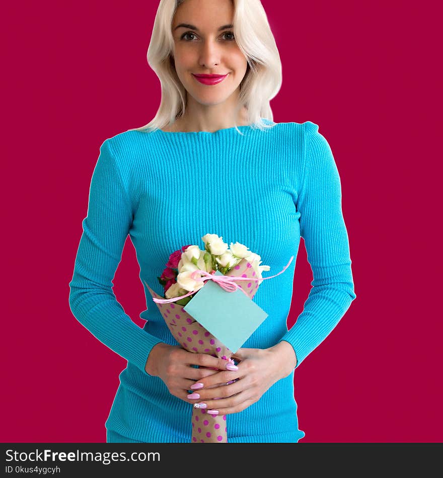 A beautiful blonde in a blue dress is holding a bouquet of roses in her hands, on a bouquet a note. A beautiful blonde in a blue dress is holding a bouquet of roses in her hands, on a bouquet a note