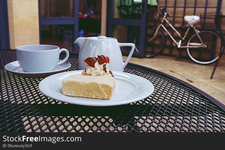 Cake on Ceramic Plate Near Teapot and Cups