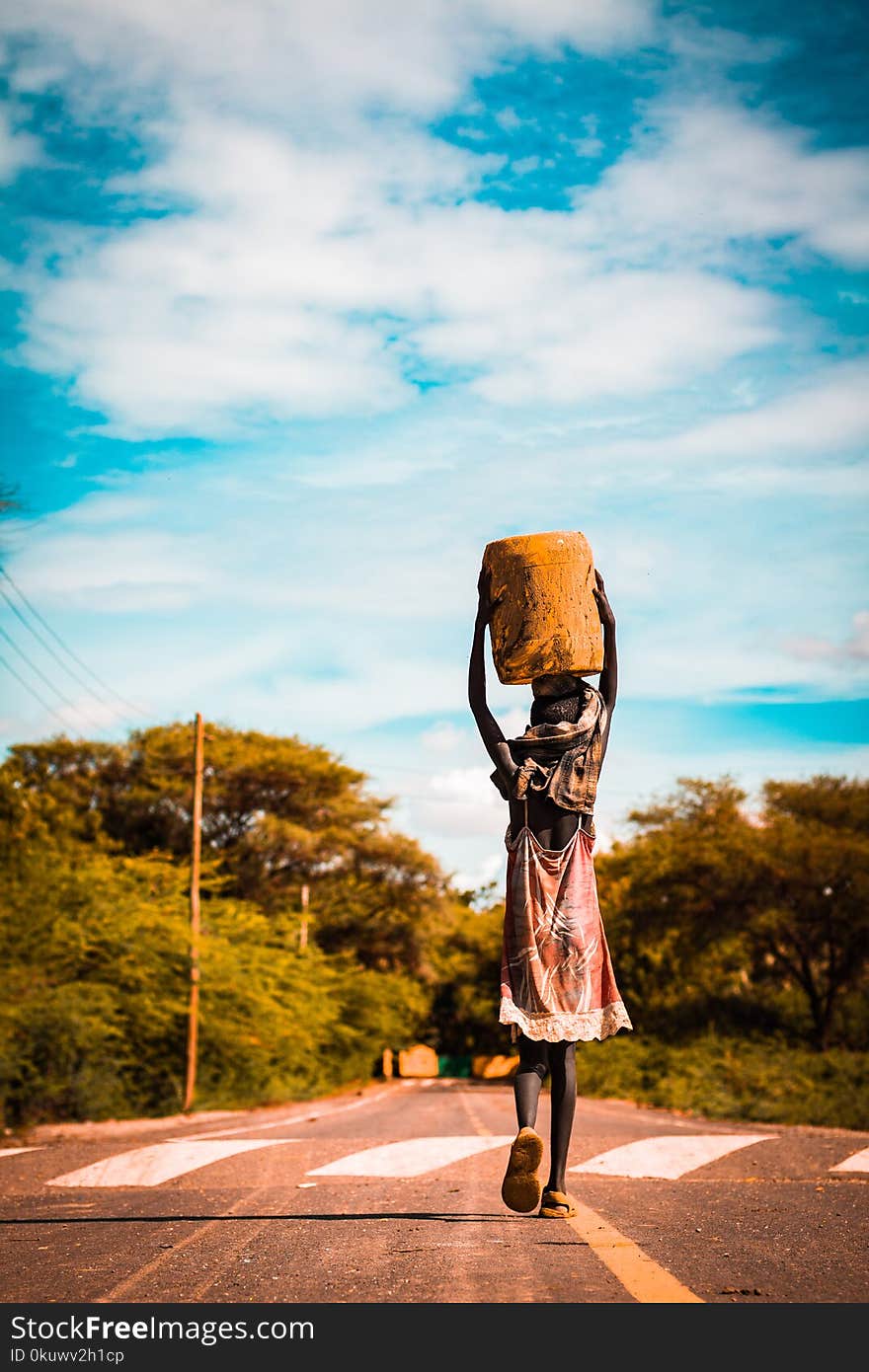 Person Carrying Container on the Head on Road